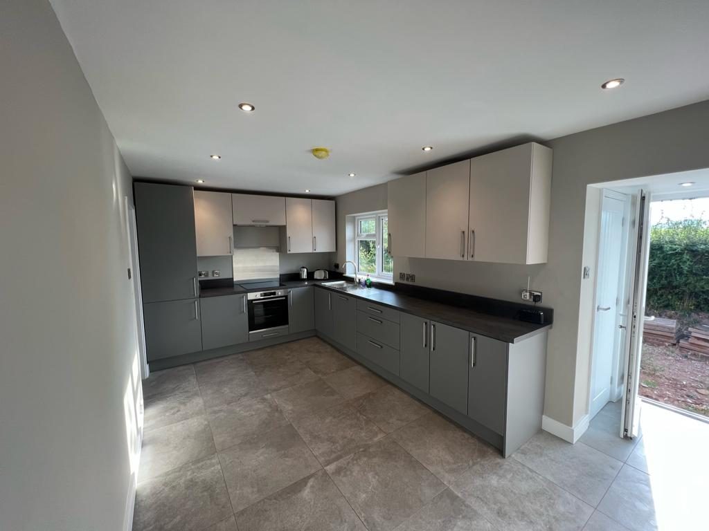 L-shaped grey handleless kitchen with light wall units