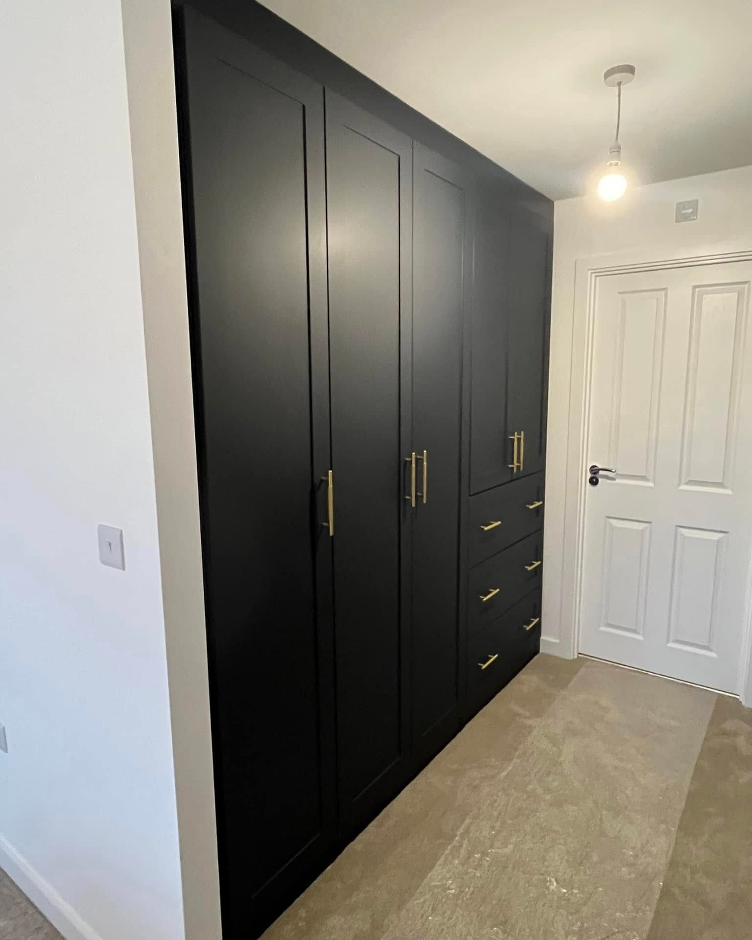 Black shaker fitted wardrobes with brass handles and a stack of drawers