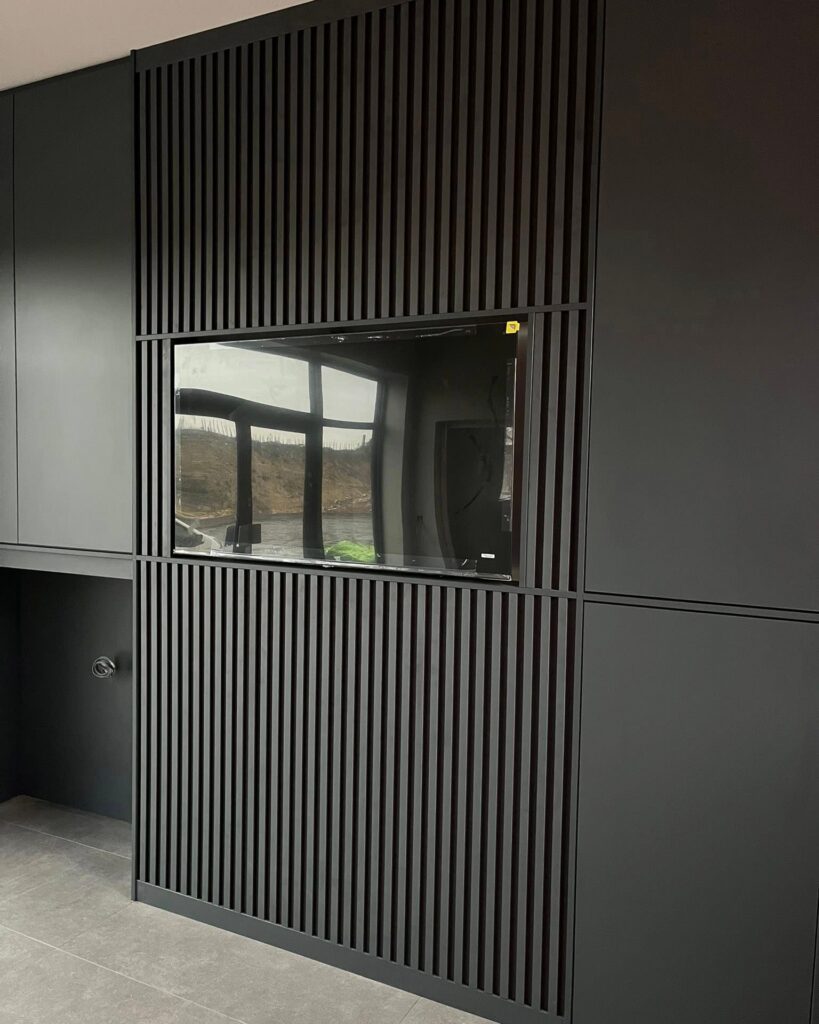 Black media wall with slatted panelling around the TV