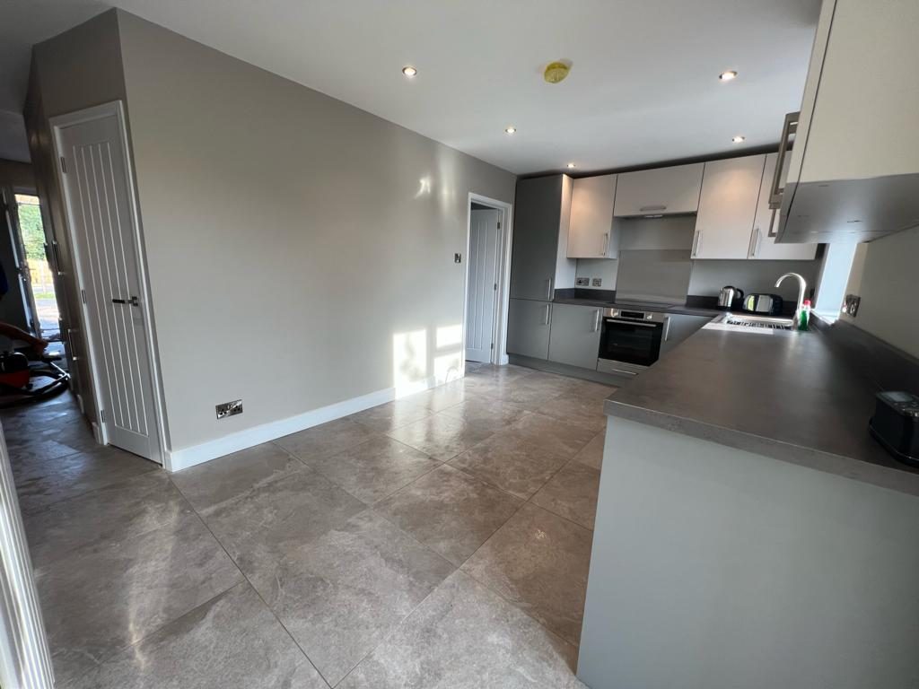 Grey two-tone handleless kitchen with a peninsula and dark worktops