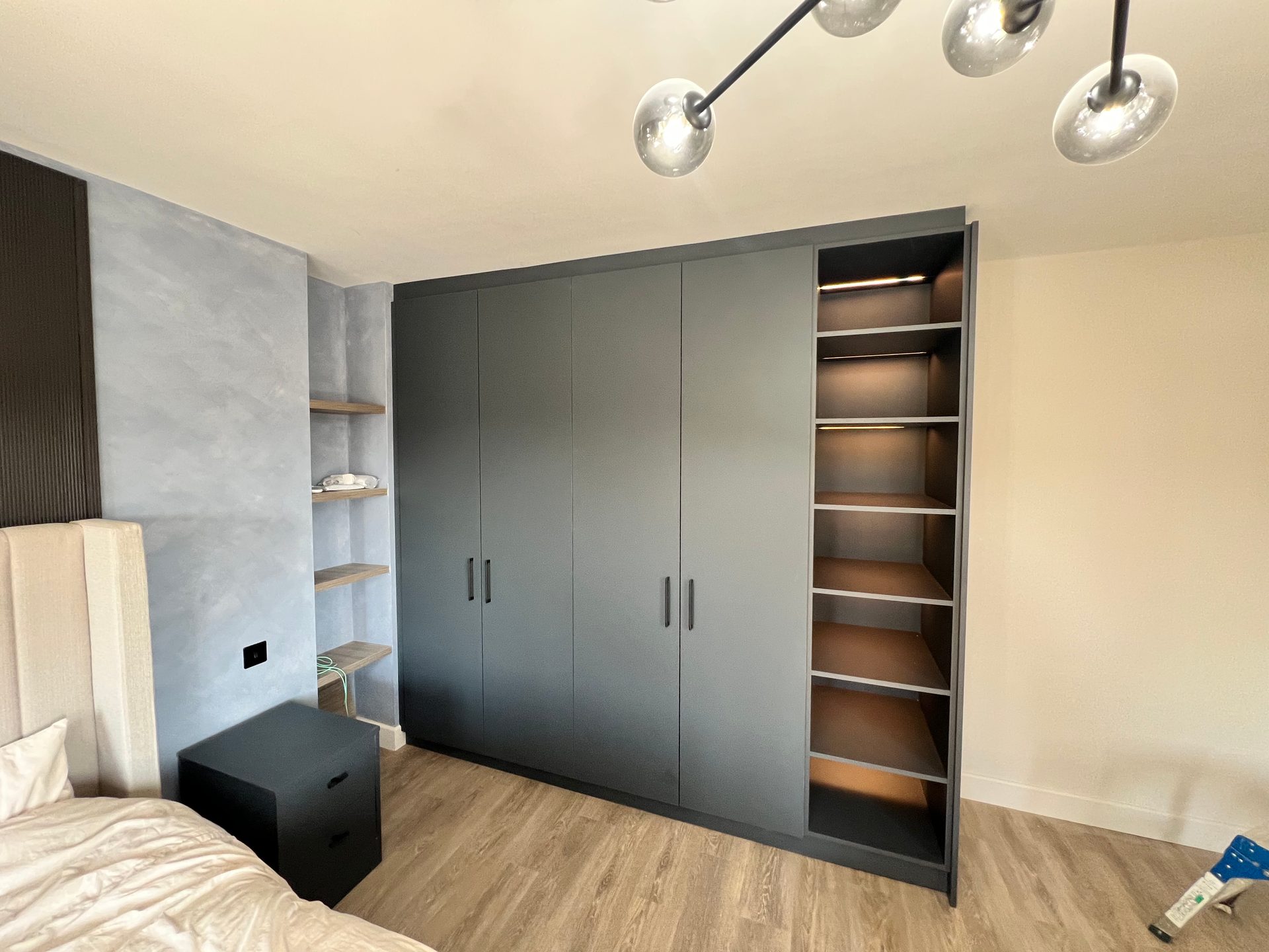 Grey fitted wardrobes with a lit open shelving column