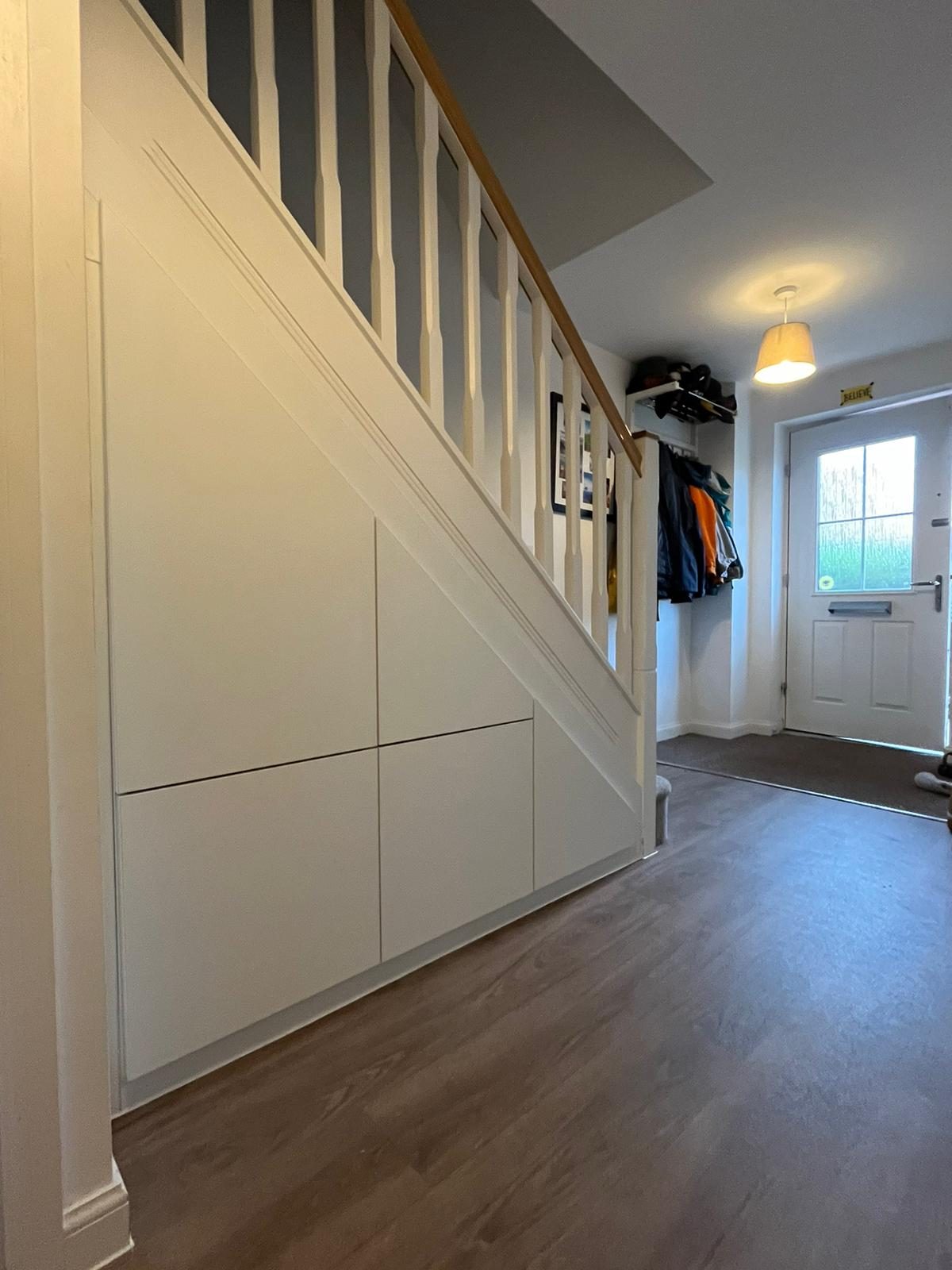 Flush handleless cupboards built under a staircase in a hallway