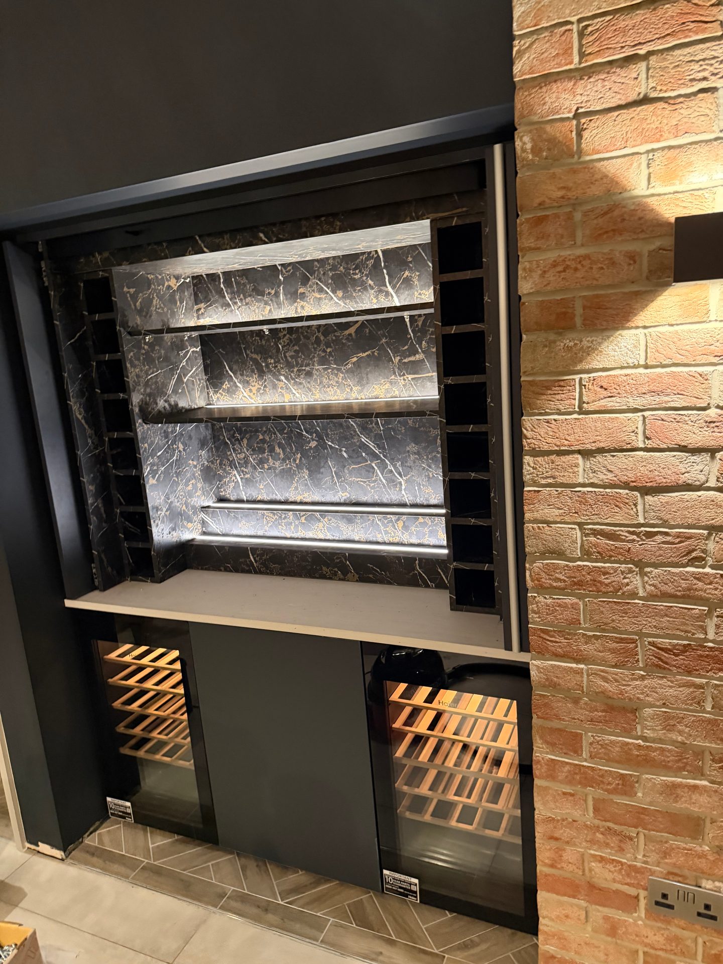 Empty home bar showing LED-lit marble-effect shelves and wine rack columns