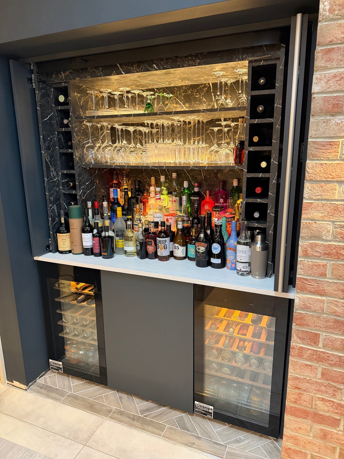 Home bar with lit marble-effect shelving, wine racks and two wine coolers