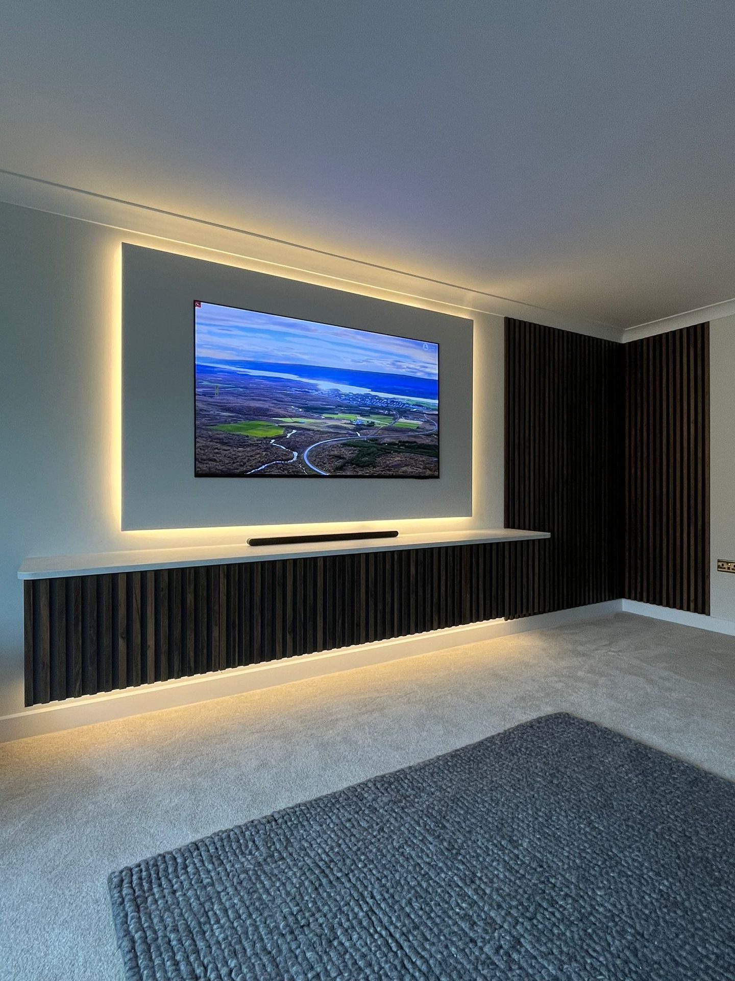 Media wall with a floating slatted base unit lit underneath