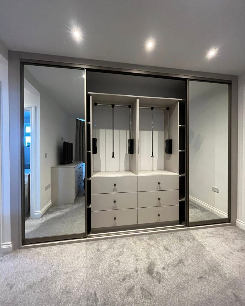 Mirrored sliding wardrobe open to show drawers and hanging space
