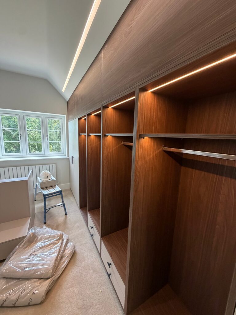 A walk-in dressing room with lit open wardrobes