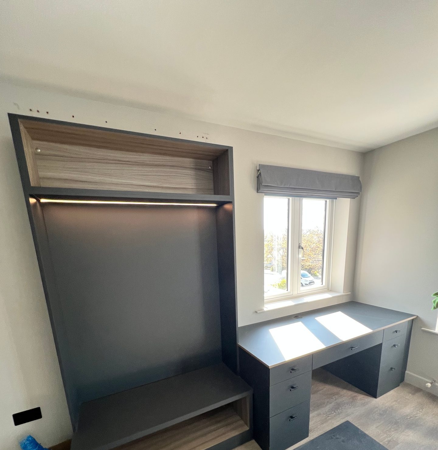 Open wardrobe bay next to a built-in desk under the window